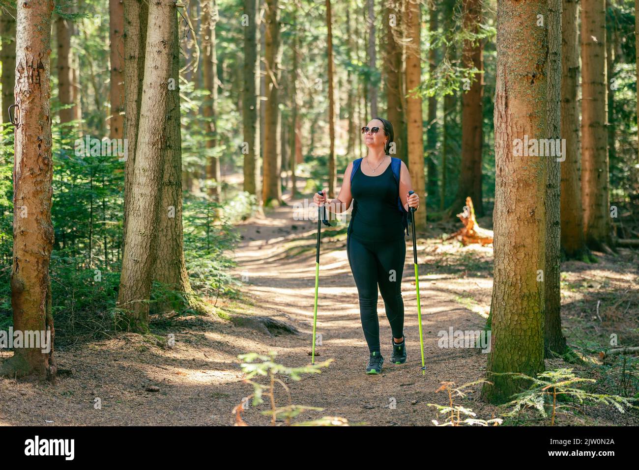 Donna cammina attraverso la foresta su un sentiero ben calpestato. Il concetto di una vita sana, godendo e giocando sport in natura Foto Stock