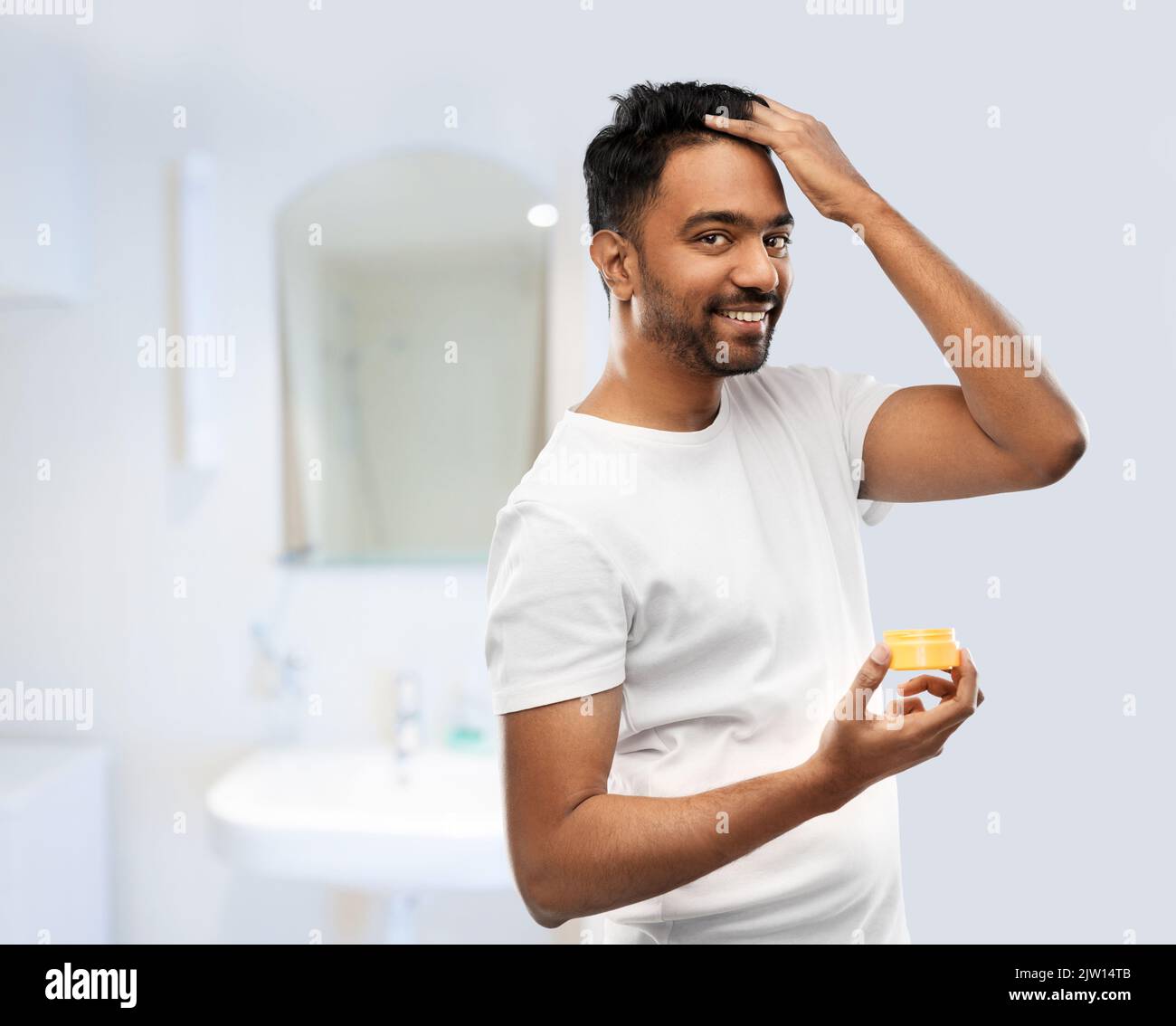 uomo che applica cera per capelli o gel per styling in bagno Foto Stock
