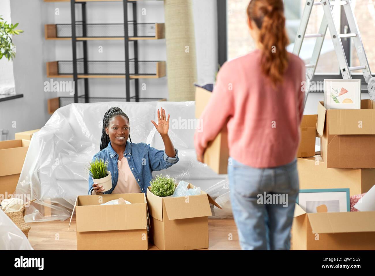 donne disimballare le scatole e muoversi verso la nuova sede Foto Stock