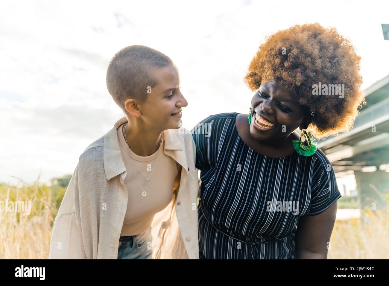 Stretta amicizia interracial. Felici ragazze di corsa mista sorridenti, abbraccianti e guardandosi l'un l'altro. Valore di culture diverse, bellezza multietnica. Foto di alta qualità Foto Stock