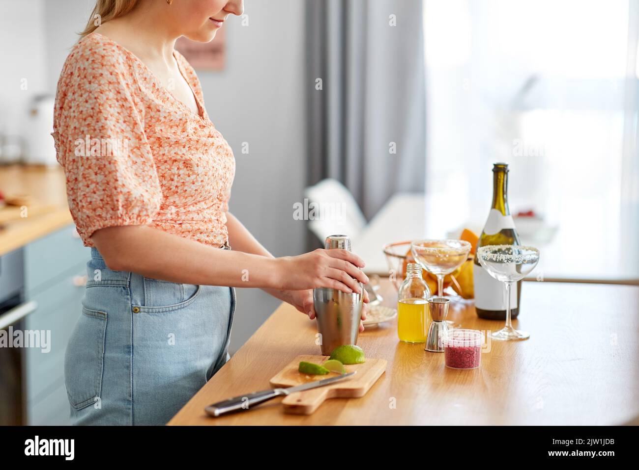 donna con shaker per preparare cocktail in cucina Foto Stock