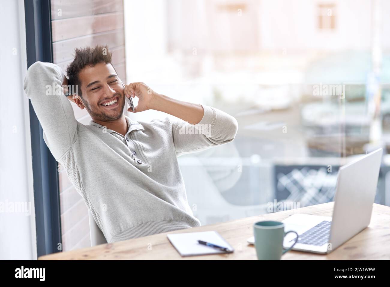 Felice di essere il suo capo. Un giovane imprenditore che parla sul suo cellulare nel suo ufficio. Foto Stock