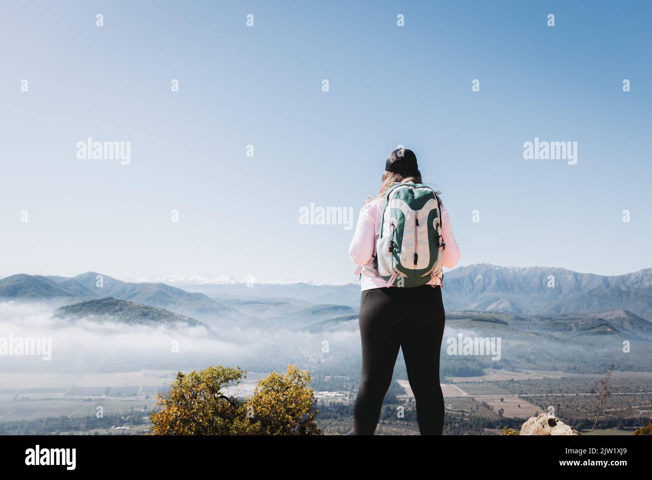 Vista posteriore giovane donna latino Plus size con zaino, in cima a una collina Foto Stock