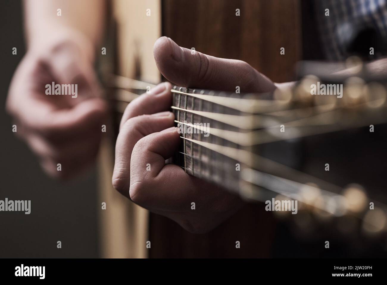 Lasciate che vi accompagni, un uomo irriconoscibile che suona una chitarra acustica a casa. Foto Stock