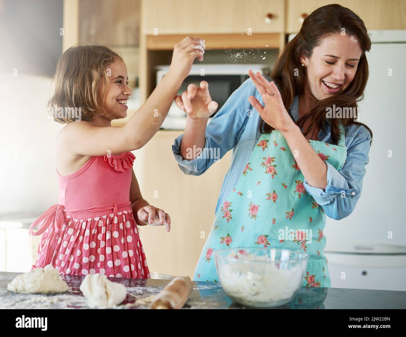 Secondo la ricetta, si dovrebbe aggiungere la farina: Una madre e sua figlia che si divertono mentre si cuocono in cucina. Foto Stock