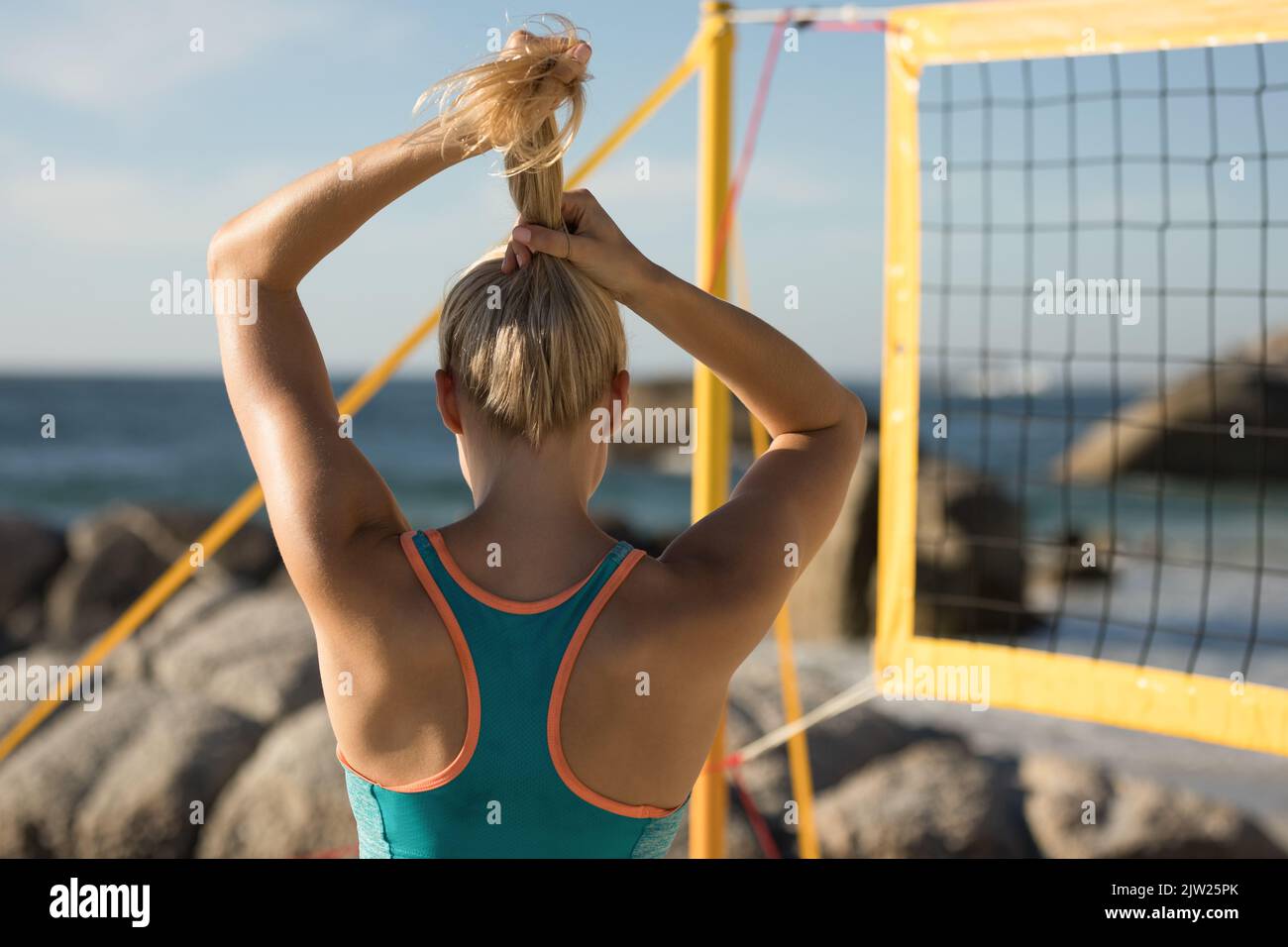 Giocatore di pallavolo femminile legano i capelli sulla spiaggia Foto Stock