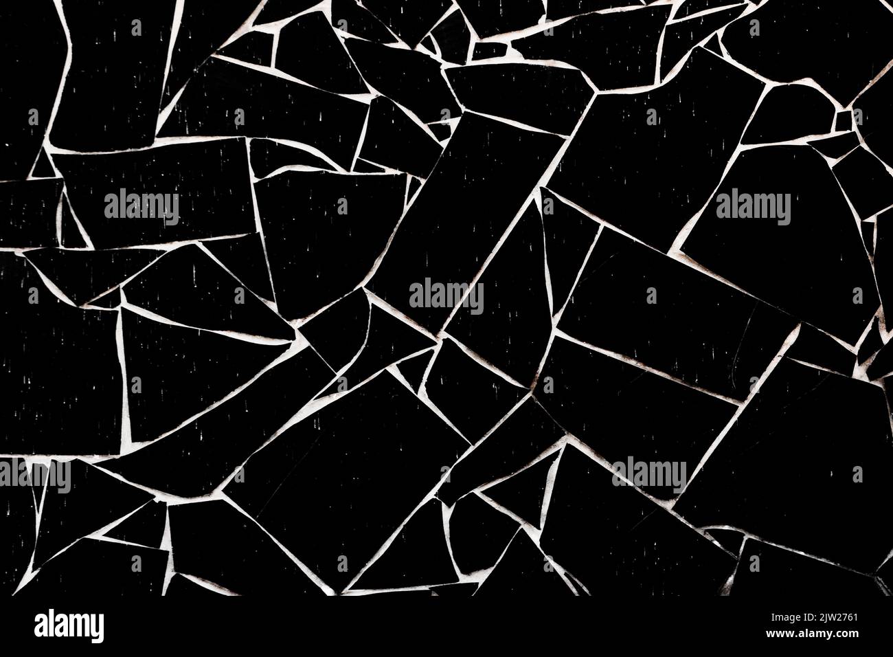 Parete in pietra nera con texture vellutata e cuciture bianche. Sfondo di una recinzione di mattoni. Foto Stock