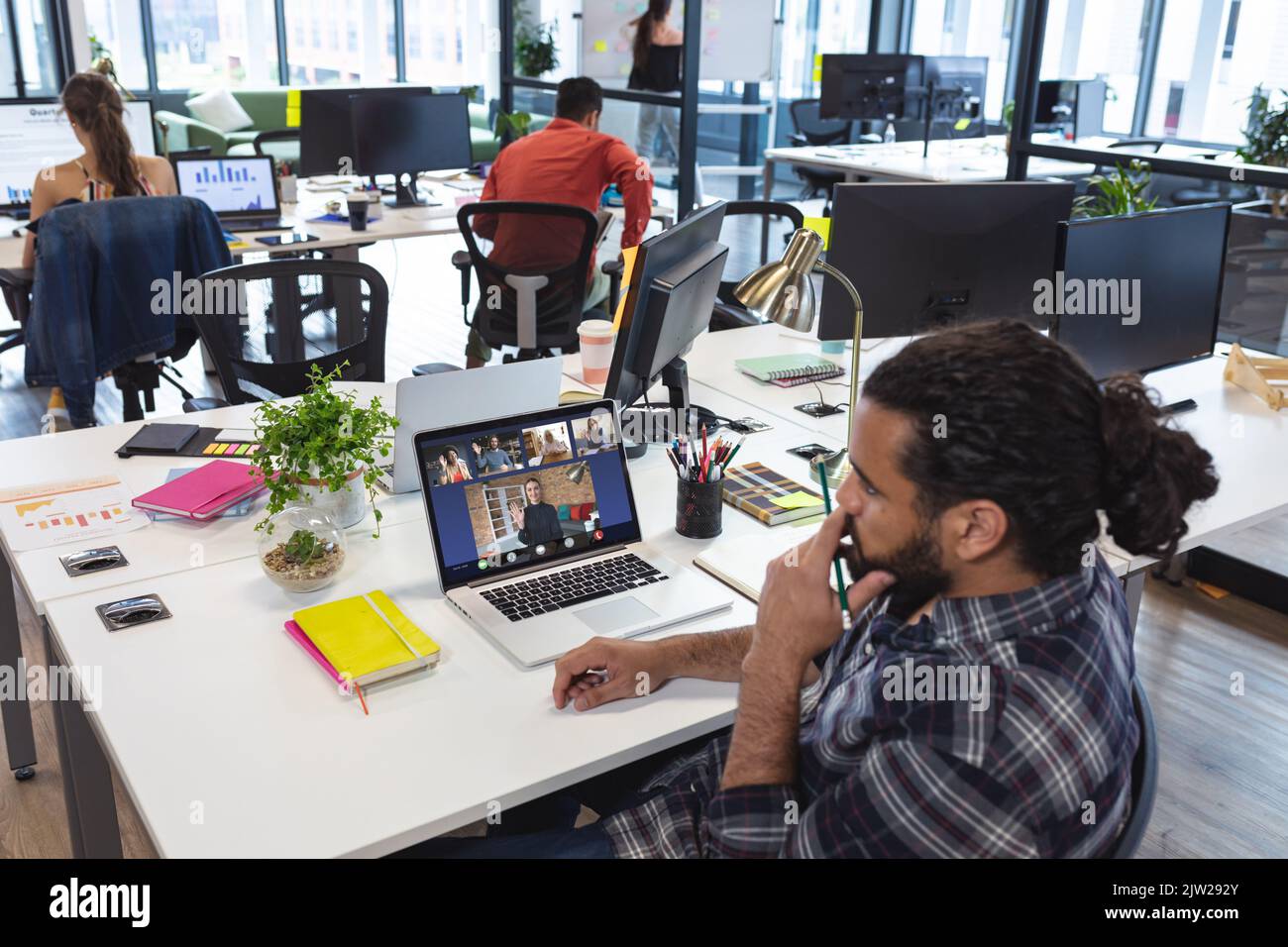 Uomo d'affari biraciale che partecipa a una riunione online tramite computer portatile mentre lavora in ufficio Foto Stock