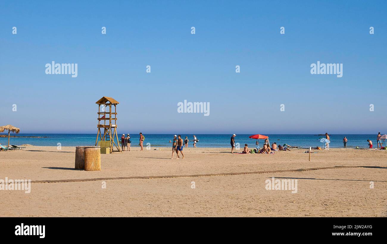 Turisti che camminano sulla spiaggia, torre di guardia, cielo blu senza nuvole, spiaggia di sabbia, spiaggia di Elafonissi, Creta sud-ovest, isola di Creta, isole greche Foto Stock