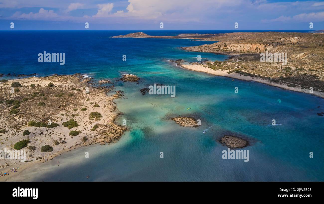 Fucilato, isolotto roccioso, kite surfisti, spiaggia sabbiosa, costa rocciosa, promontorio, mare verde e turchese, cielo blu con nuvole bianche, spiaggia di Elafonissi Foto Stock