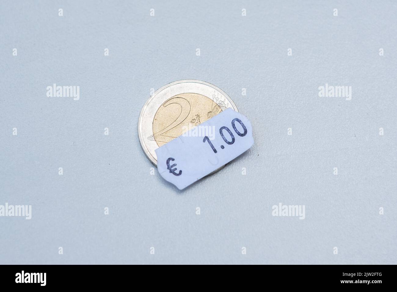 Due monete in euro con un cartellino in euro. Attenzione selettiva all'etichetta. Inflazione in Europa, iperinflazione, svalutazione del concetto di moneta fiat. Foto Stock