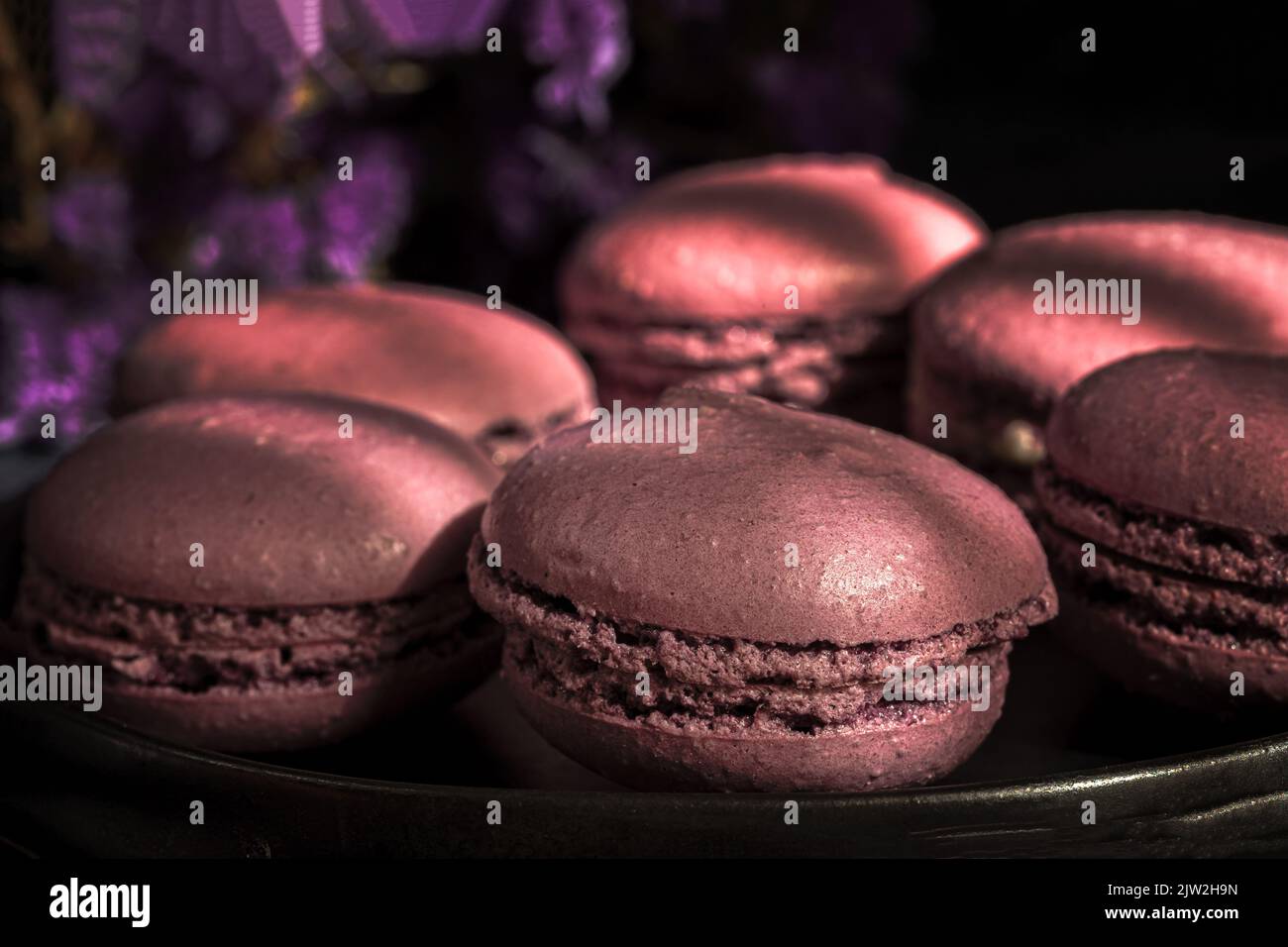 Deliziosi amaretti dolci di colore viola insieme sul tavolo illuminato al sole al mattino Foto Stock