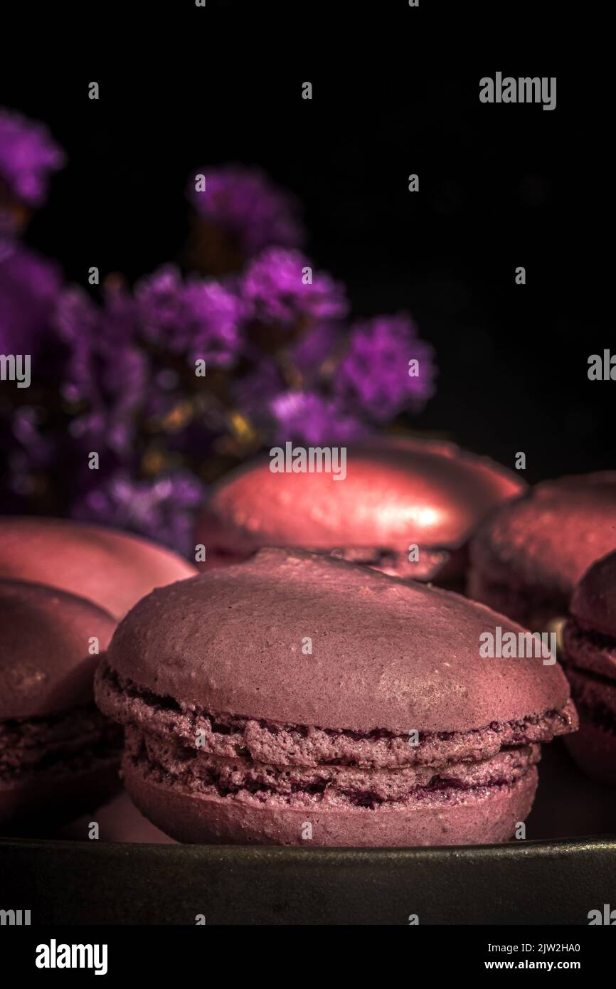 Deliziosi amaretti dolci di colore viola insieme sul tavolo illuminato al sole al mattino Foto Stock