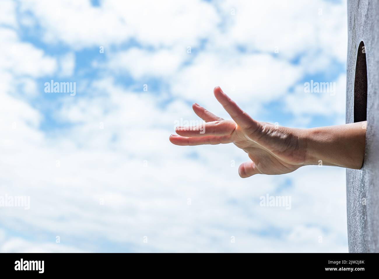 Angolo basso di una persona irriconoscibile che si stacca dalla buca rotonda contro il cielo blu nuvoloso mentre si passa il tempo nel parco giochi in estate. Foto Stock