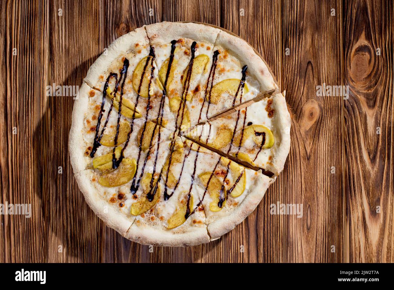 Deliziosa pizza dolce con mela, cannella, cioccolato su sfondo di legno. Pizza dessert. Vista dall'alto Foto Stock