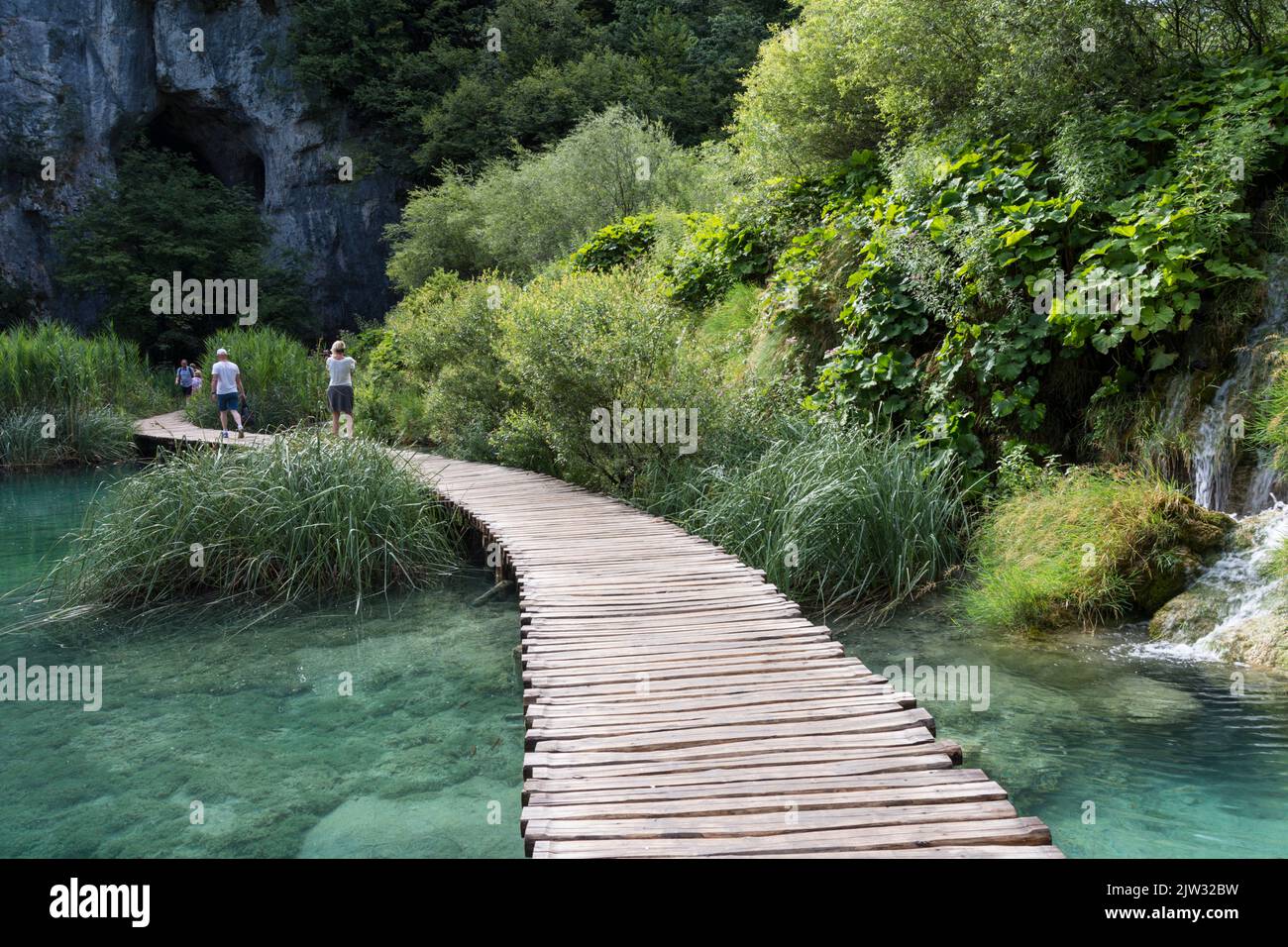 I turisti che camminano a bordo di una passeggiata su una delle numerose piscine e laghi del Parco Nazionale dei Laghi di Plitvice, Croazia, Europa. Foto Stock