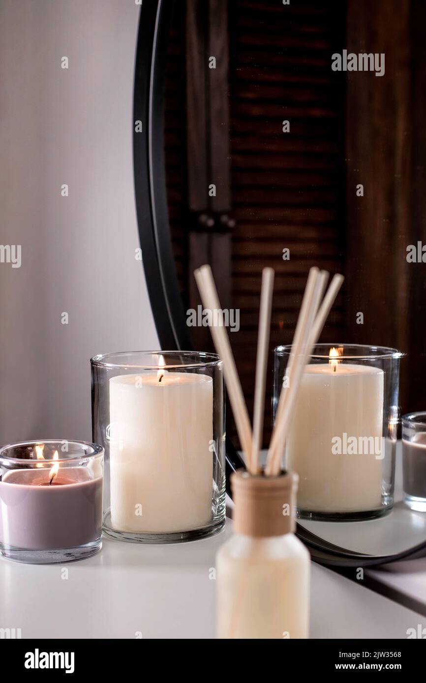Deodorante per ambienti in una bottiglia di vetro e candele profumate nei portacandele. Atmosfera casalinga. Fragranze per la casa. Foto Stock