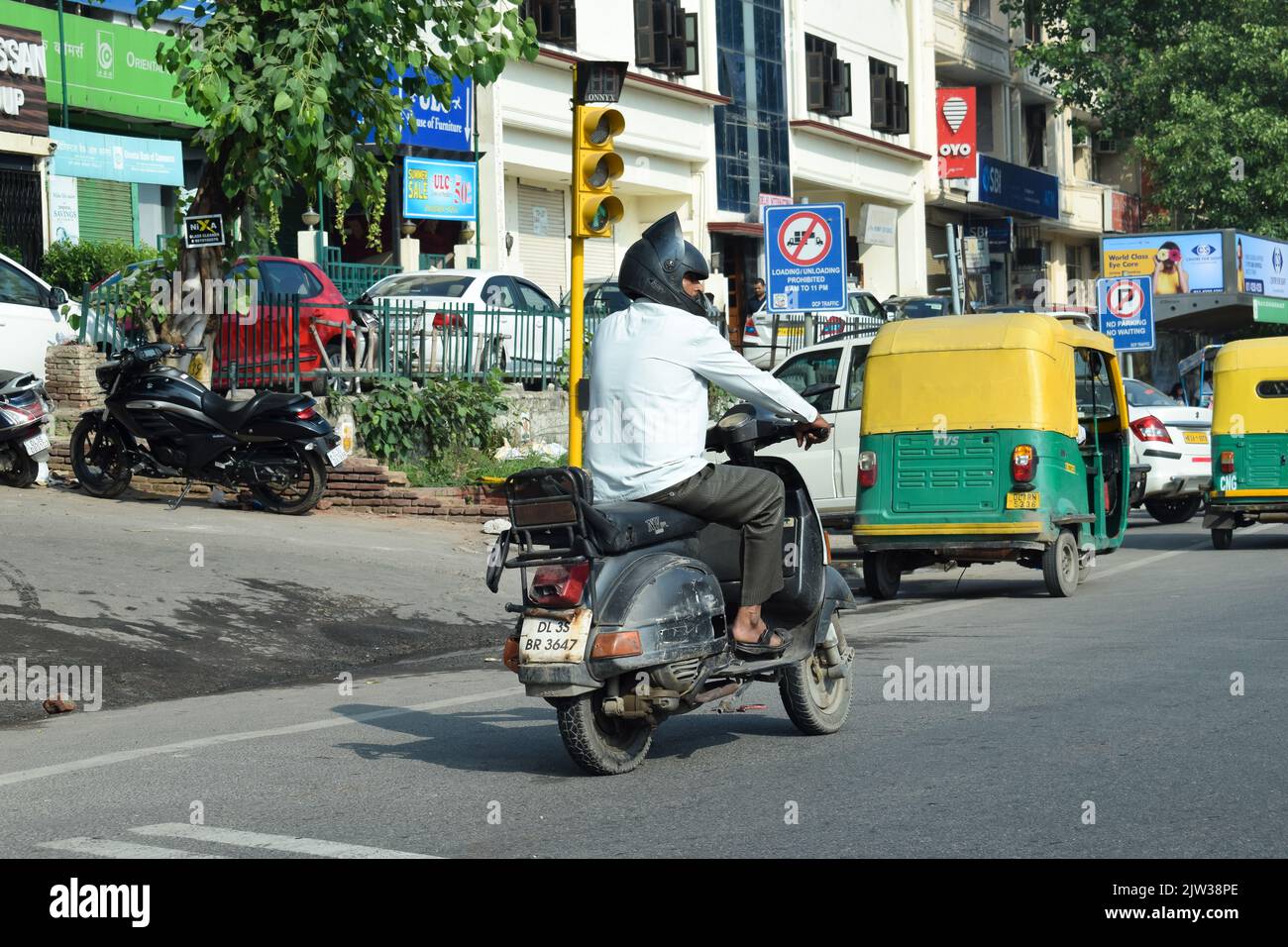 Uomo indiano a cavallo scooter su strada. Foto Stock