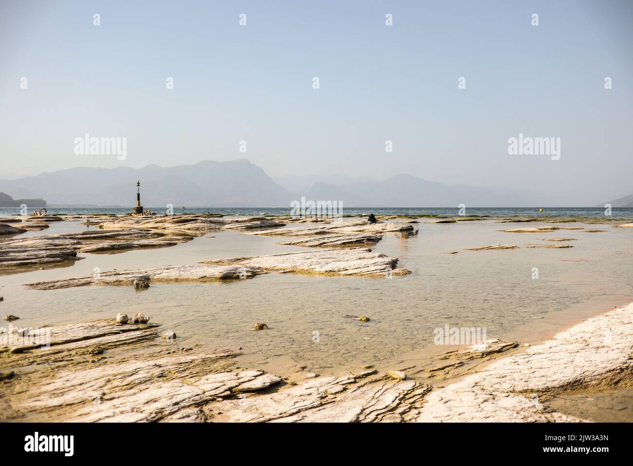 Spiaggia Giamaica durante il giorno d'estate a Sirmione. Rocky Beach sul Lago di Garda. Bella scena del lago in Italia. Foto Stock
