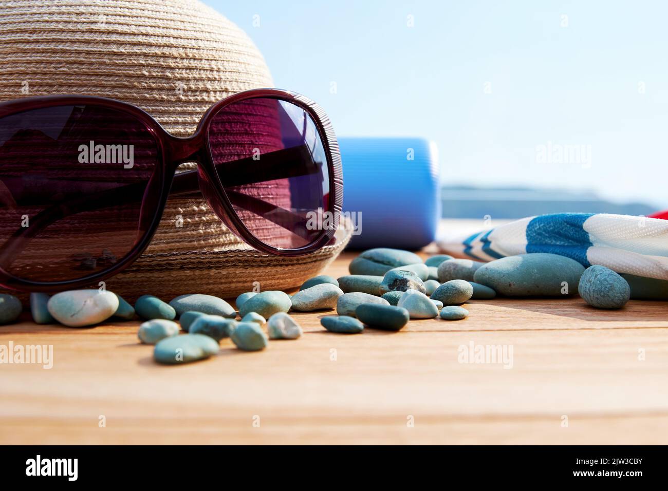 Elegante cappello in paglia, occhiali da sole, accessori marini con il paesaggio sul retro. Mare e spiaggia relax e vacanze sfondi Foto Stock