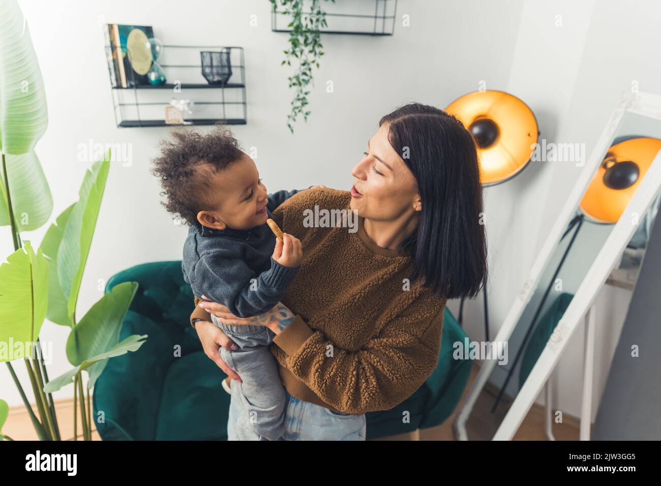 mamma che tiene il suo figlio amato e giocare, medium shot soggiorno felice famiglia. Foto di alta qualità Foto Stock