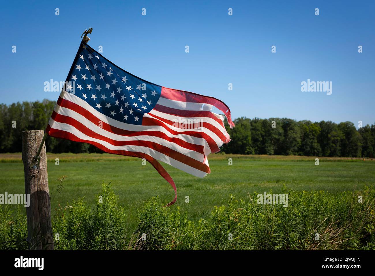 Una bandiera, attaccata ad un palo di recinzione, ondeggia nel vento a Francis Creek vicino Manitowoc, Wisconsin. Foto Stock