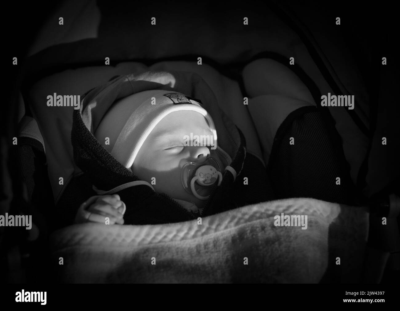 Il bambino di cinque mesi dorme con il succhietto in passeggino durante la passeggiata Foto Stock