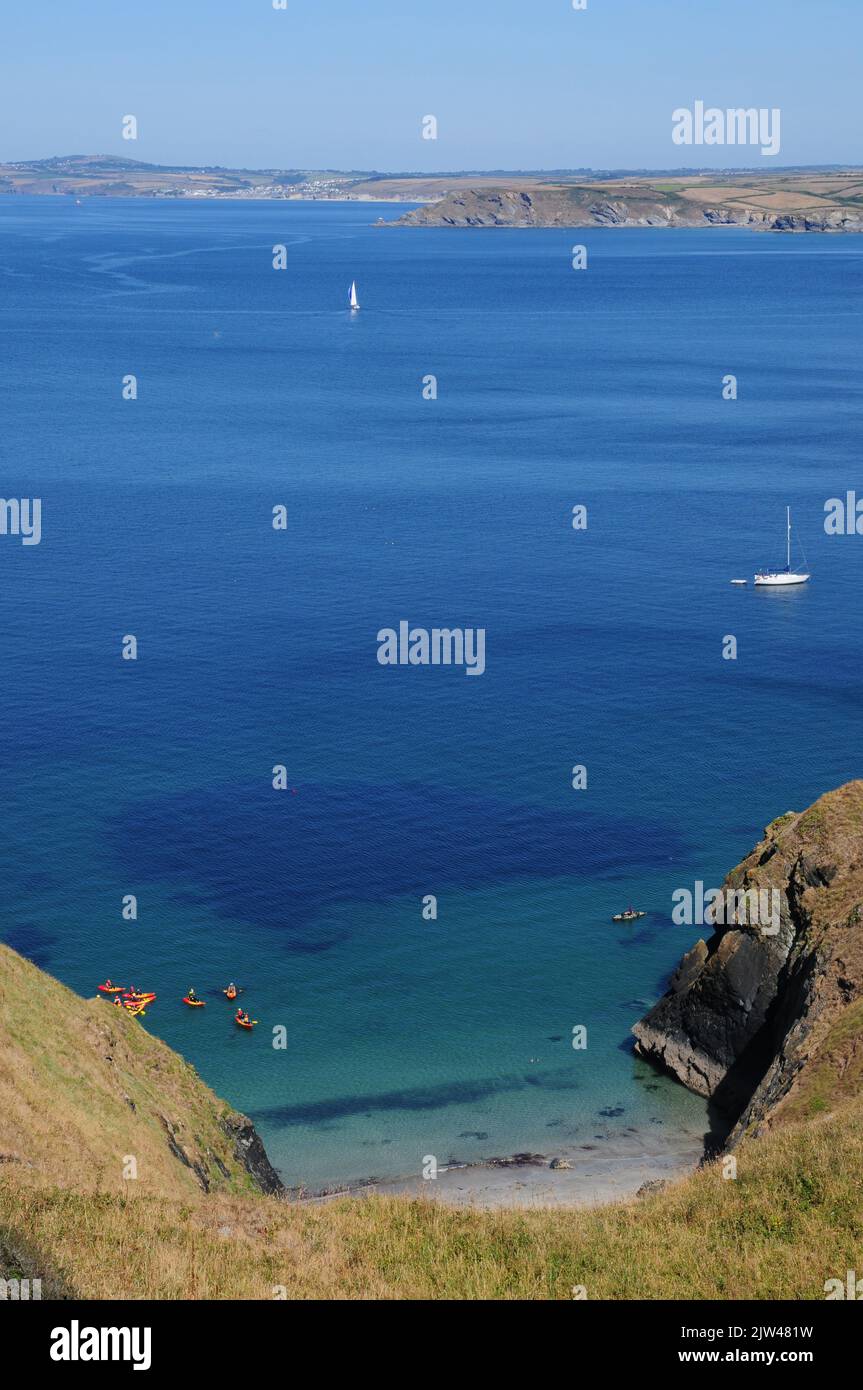 I kayakers atterrano su una spiaggia di sabbia isolata in una giornata di sole e mare calmo. Foto Stock