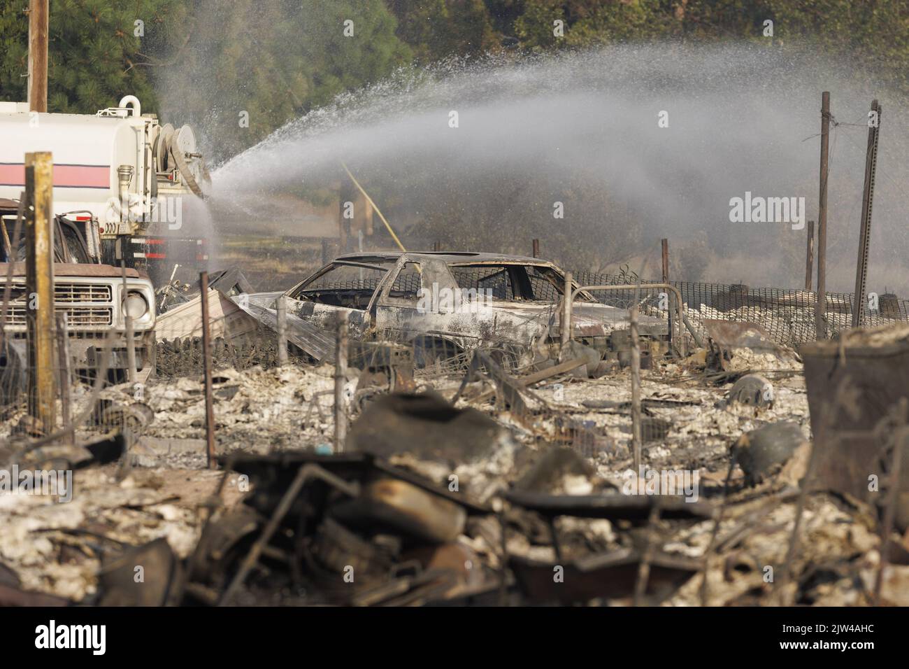 Weed, Stati Uniti. 23rd ago, 2022. Un Water Tender spruzza acqua su parti di un quartiere distrutto dopo che il Mill Fire ha bruciato attraverso parti di Weed, California Sabato, 3 settembre 2022. Foto di Peter DaSilva/UPI Credit: UPI/Alamy Live News Foto Stock