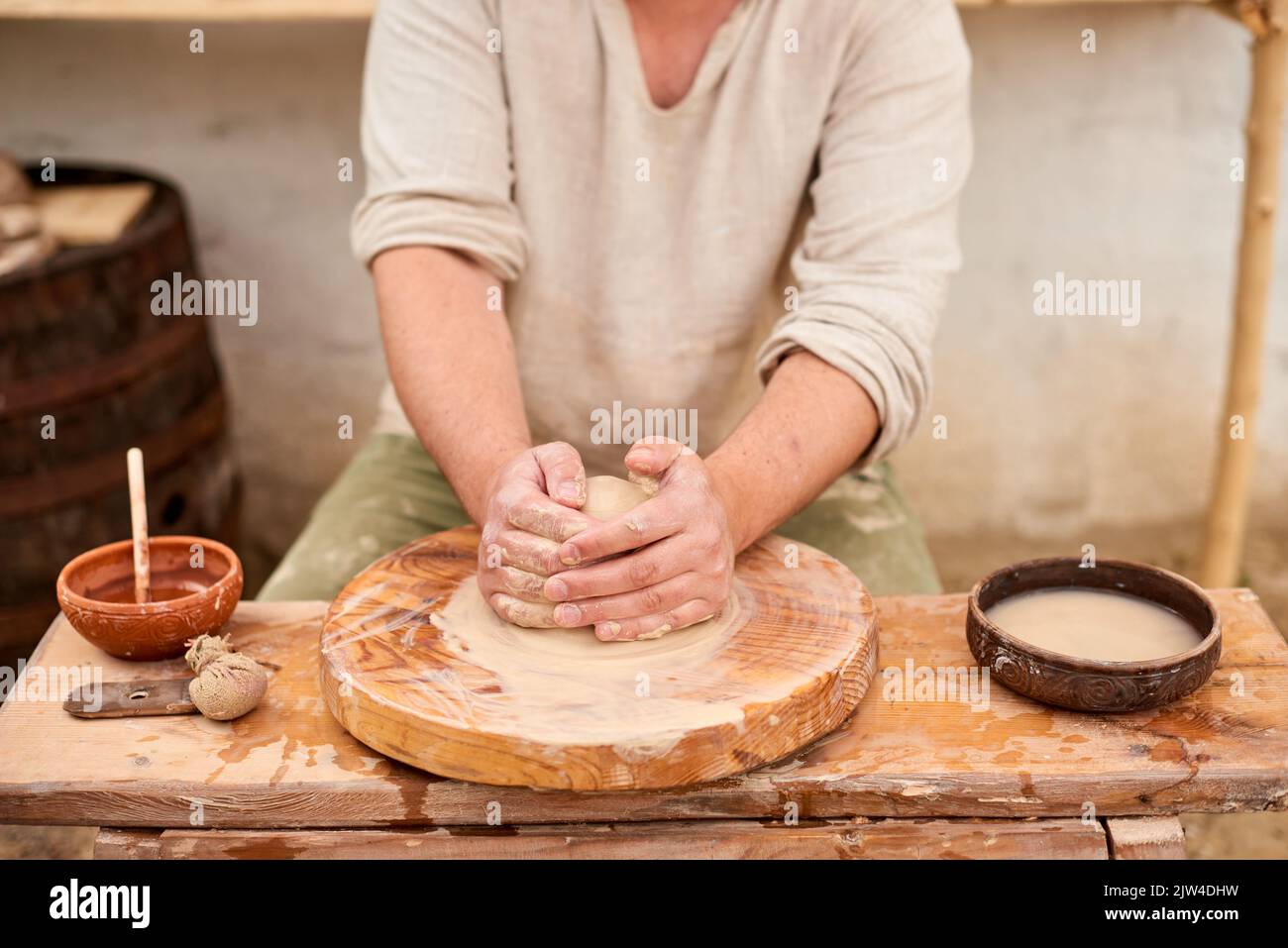 Potter con pentola di creta bagnata in mani. Le mani dell'uomo di Crafter di ceramica scolpiscono in creta Foto Stock