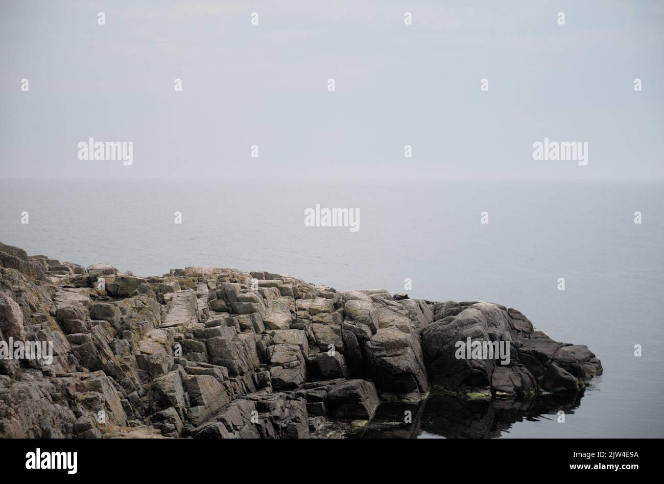Spiaggia rocciosa e mare calmo sullo sfondo, l'arcipelago di Christiansoe Danimarca Foto Stock