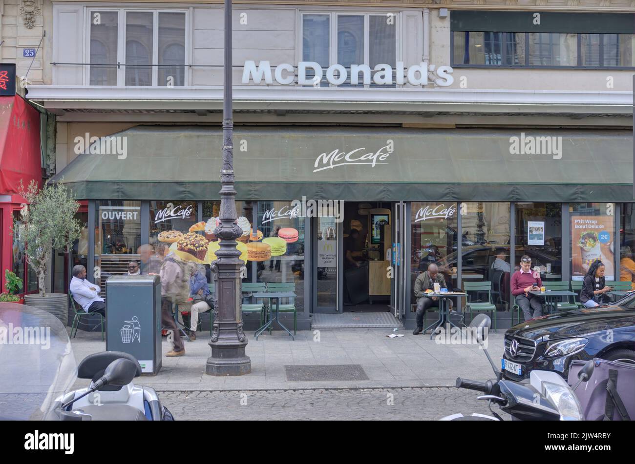 Parigi, Francia - 30 maggio 2022: Esterno del ristorante McDonald's (McCafe) di fronte alla stazione ferroviaria Gare du Nord con i clienti e pedina sfocata Foto Stock