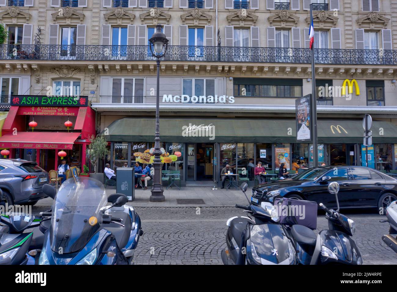 Parigi, Francia - 30 maggio 2022: Esterno del ristorante McDonald's (McCafe) di fronte alla stazione ferroviaria Gare du Nord con i clienti e i veicoli parcheggiati in avanti Foto Stock