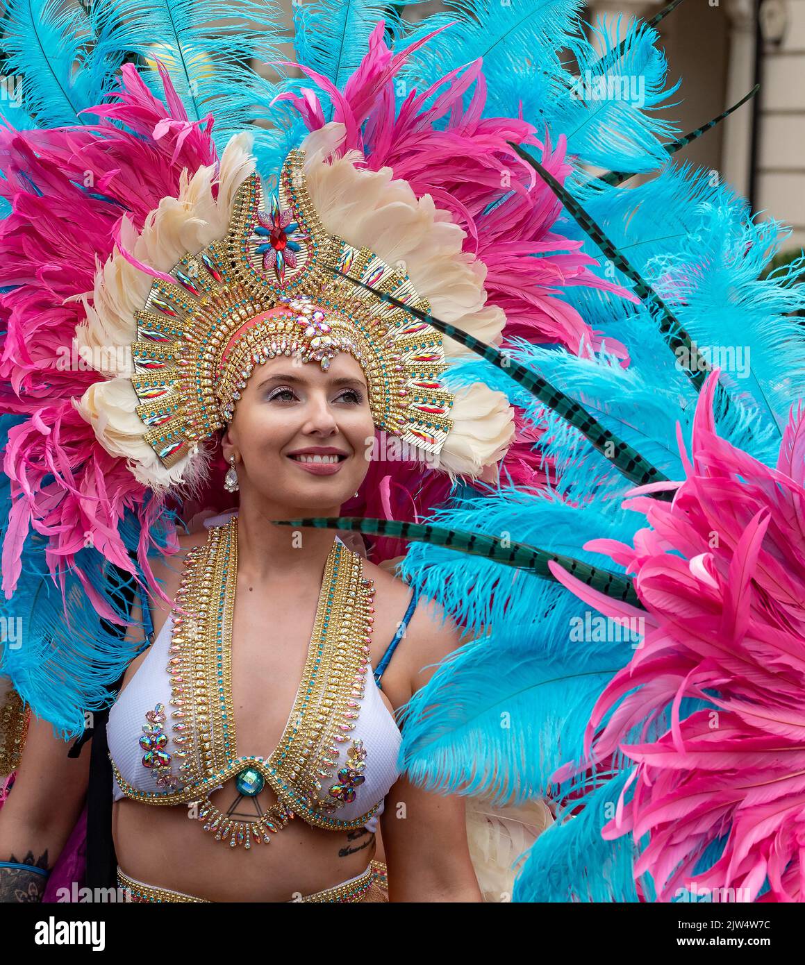 Londra, Inghilterra, Regno Unito - 29 agosto 2022: Ritratto di una donna, vestita per il carnevale con piume blu e rosa per le strade, a Notting Hill Foto Stock