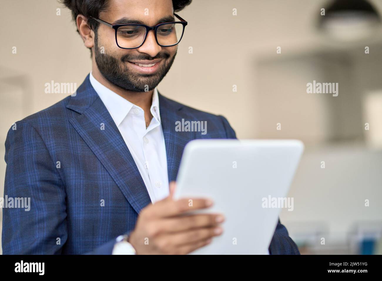 Giovane e sorridente manager indiano che indossa una tuta con un tablet digitale. Foto Stock