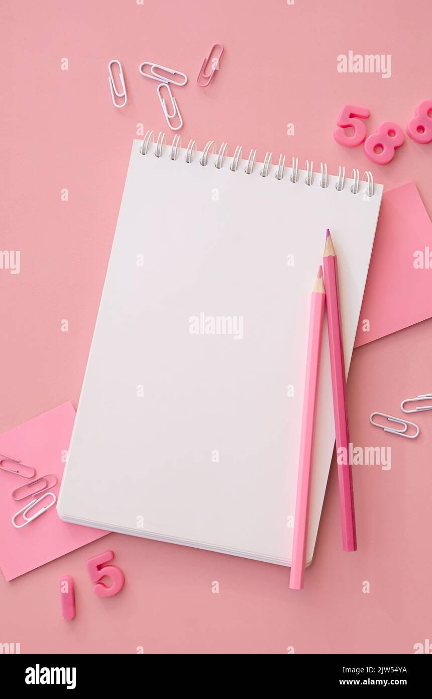 Accessori scolastici quaderno aperto su sfondo rosa, piatto, verticale. Foto Stock