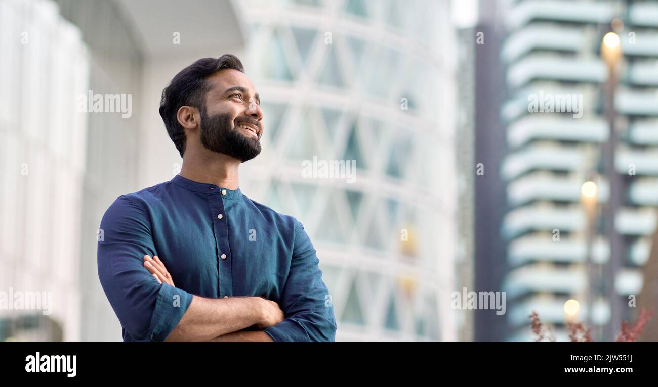 Felice ricco uomo indiano di affari in piedi nella grande città pensando alla visione futura. Foto Stock
