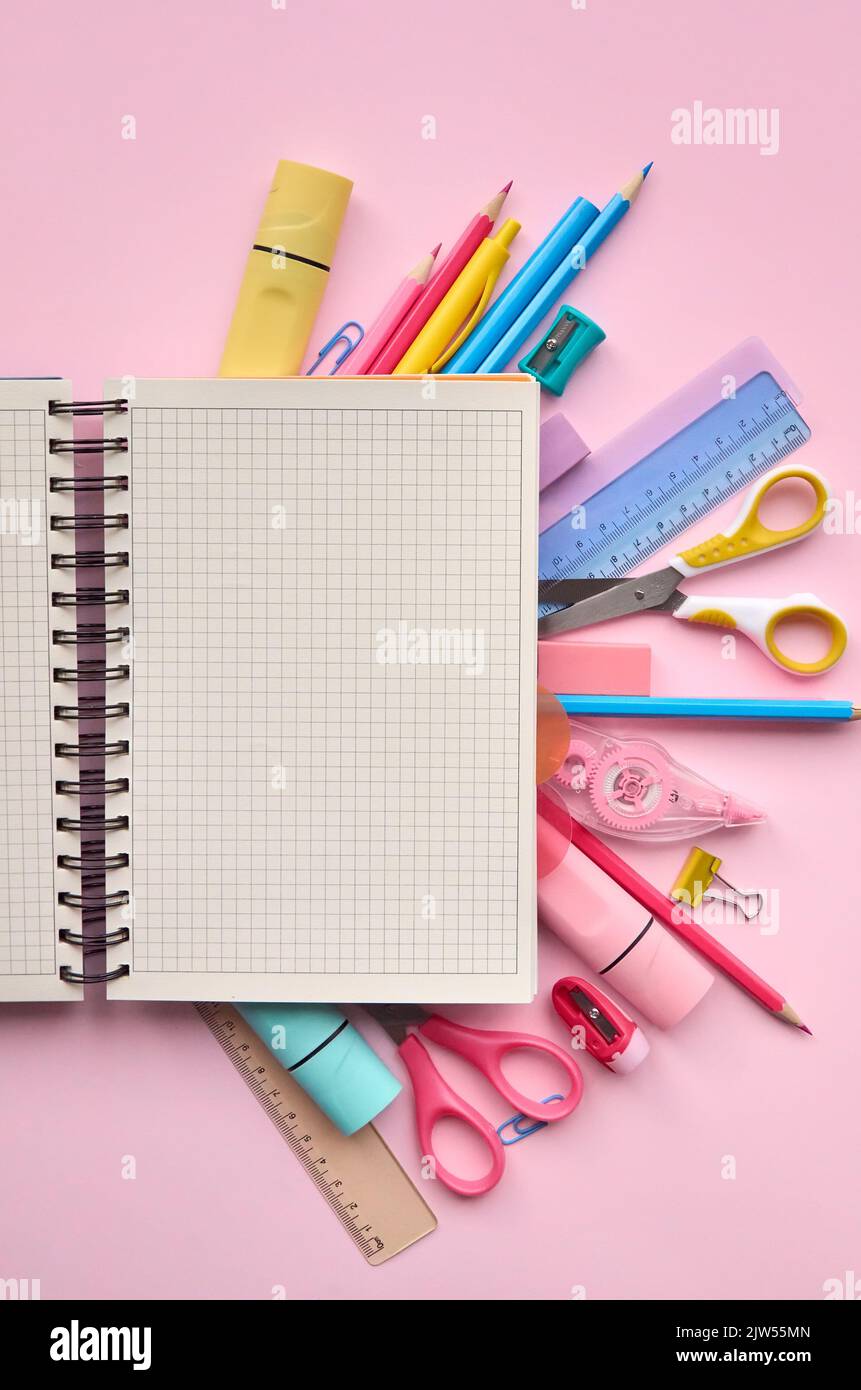 Il notebook aperto e la scuola fornisce gli accessori dei prodotti su sfondo pastello. Foto Stock