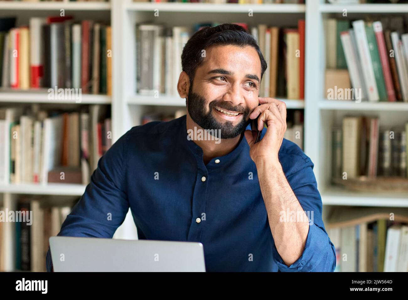 Uomo indiano felice di affari che lavora in ufficio che parla sul telefono che fa la chiamata. Foto Stock