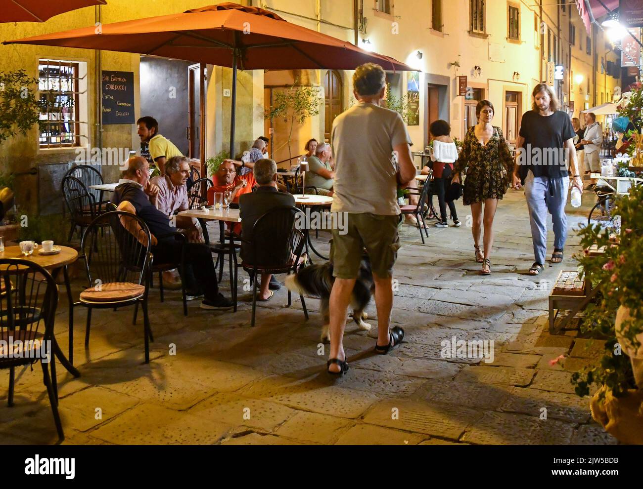 La strada principale e stretta del borgo medievale affollata di gente di sera, Castagneto Carducci, Livorno, Toscana, Italia Foto Stock