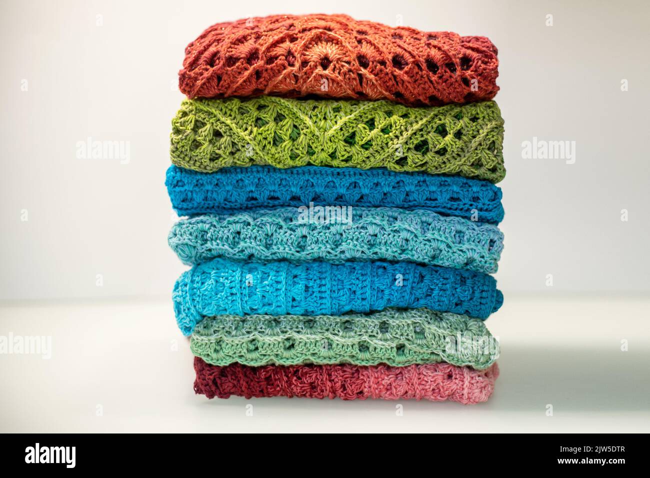 una pila di oggetti a maglia multicolore su sfondo bianco. Foto Stock