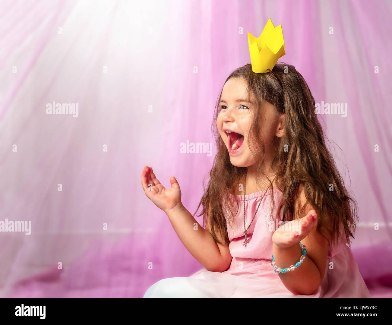 Ragazza vestita come una principessa sul letto sorride e guarda via Foto Stock