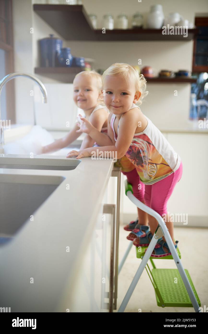 Guarda, possiamo raggiungerli ora. Ritratto di due ragazze in piedi su una scala in un lavello da cucina. Foto Stock