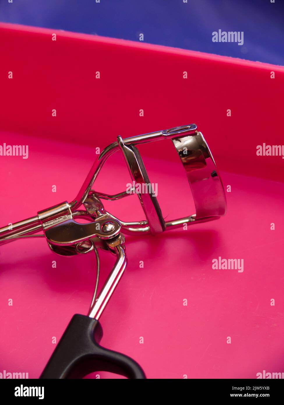 Primo piano di un arricciacapelli con ciglia in una scatola rosa. Foto Stock