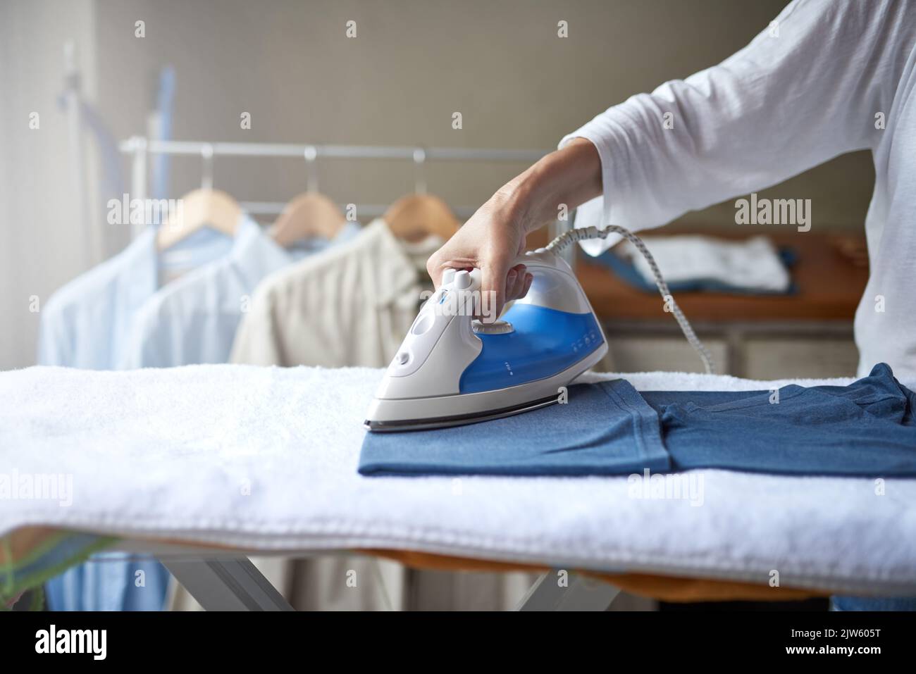 Sbarazzarsi di alcune rughe. Primo piano di una donna che stira una camicia. Foto Stock