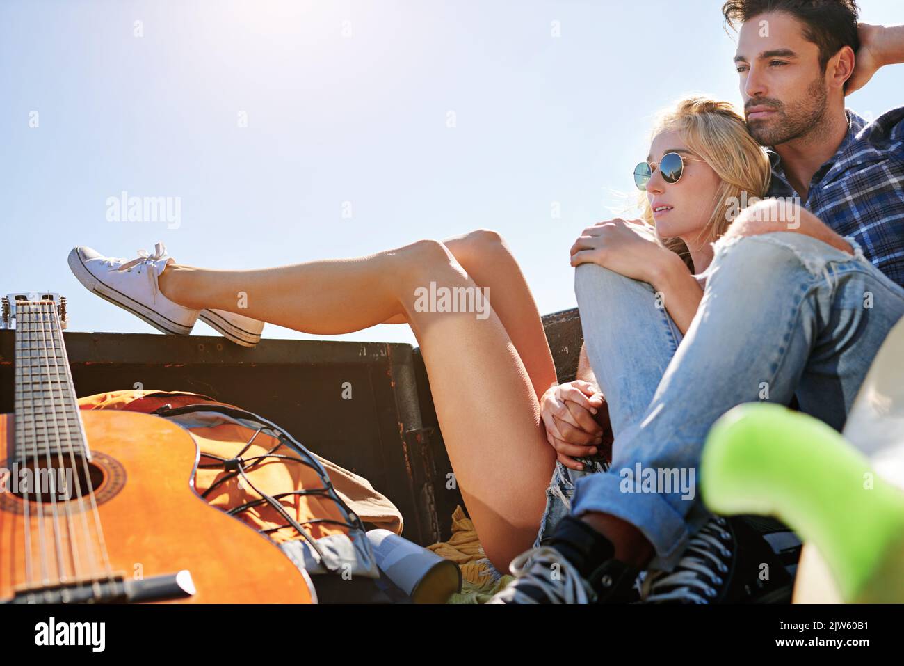 Ci piacciono i panorami, ci piace molto la strada. Una giovane coppia si rilassa sul retro di un pick-up mentre si viaggia su strada. Foto Stock