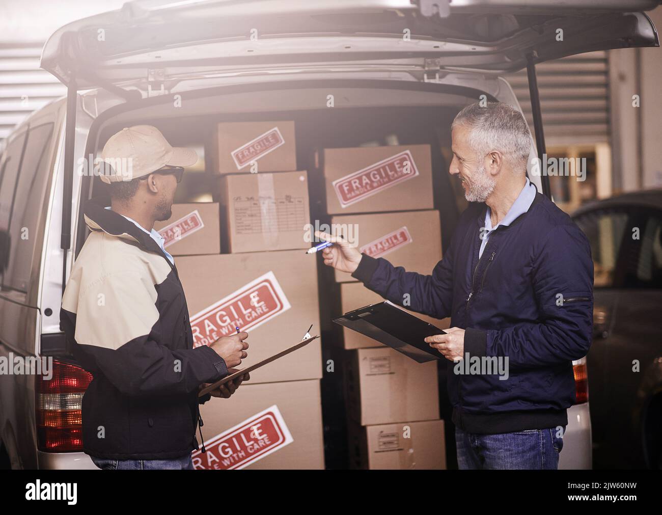 Cura per il vostro carico prezioso. Due uomini di consegna che hanno una discussione accanto ad un furgone riempito di scatole. Foto Stock