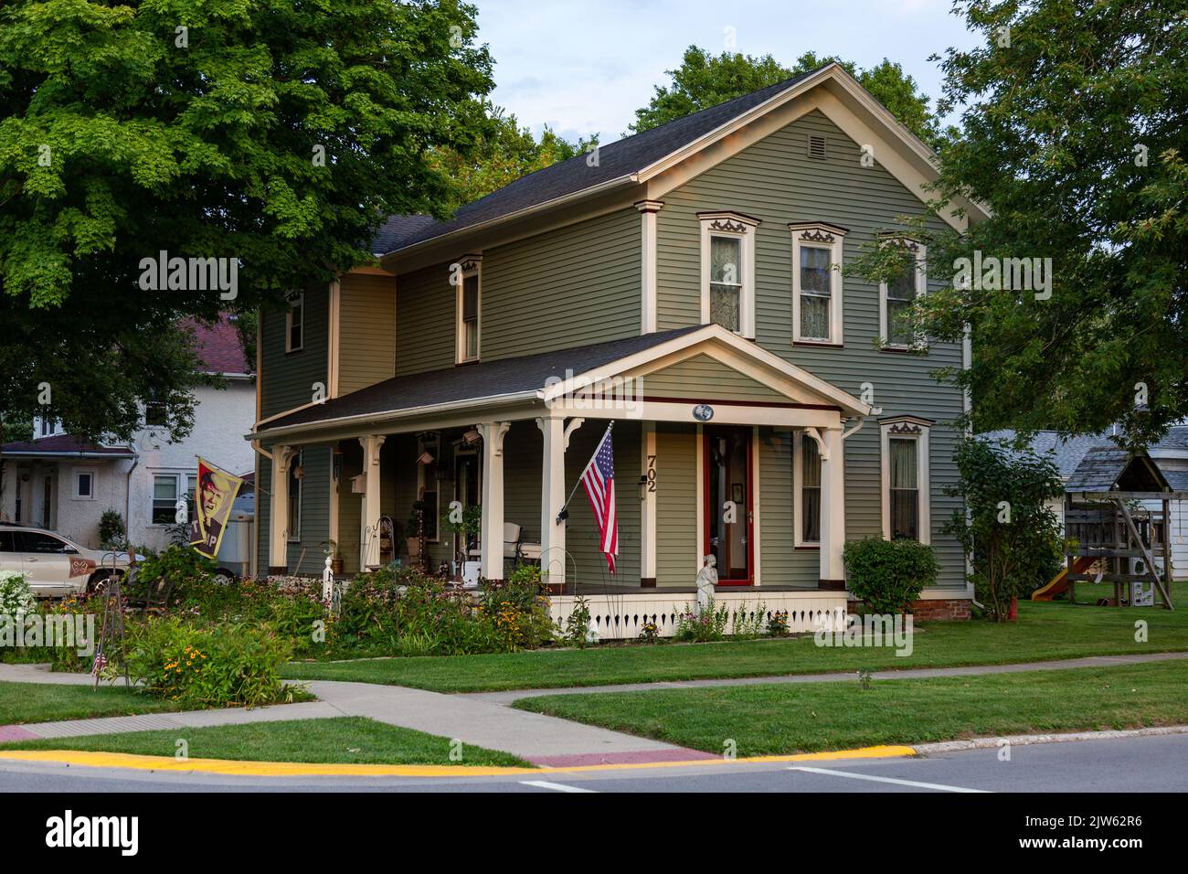 Un'esposizione patriottica della bandiera americana dal portico di una casa su un lotto d'angolo in Auburn, Indiana, Stati Uniti. Foto Stock