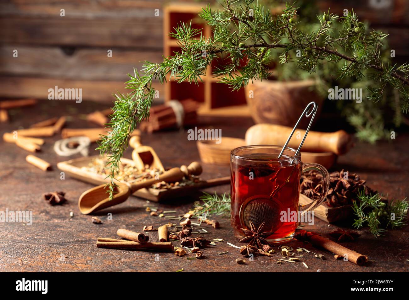 Tisane con cannella, anice ed erbe secche. Tè alle erbe con ginepro twig su un vecchio tavolo marrone. Foto Stock