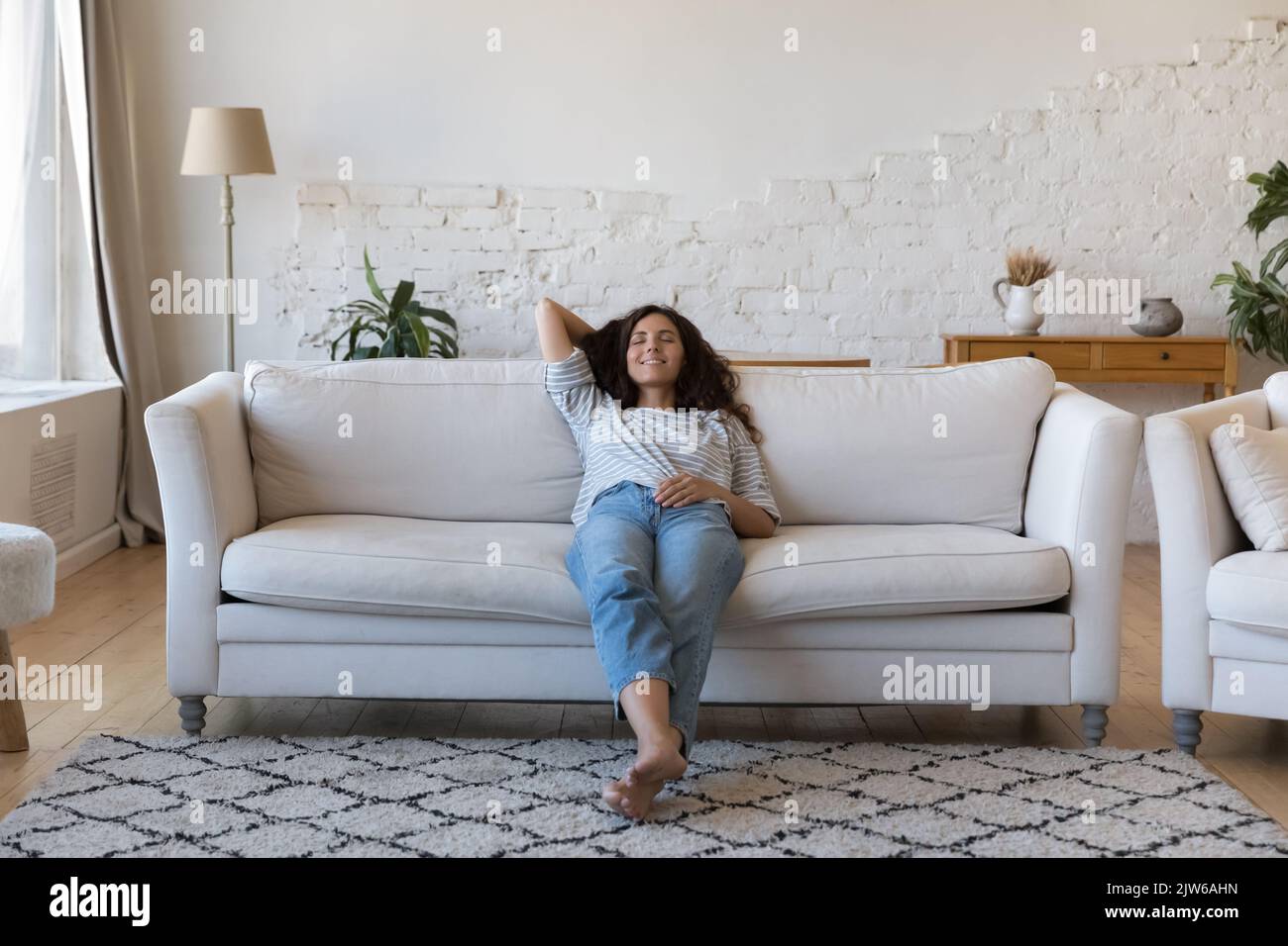Bella donna Latina rilassarsi sul divano a casa Foto Stock